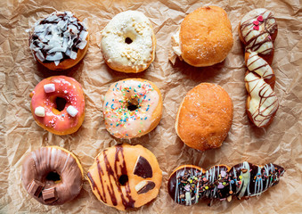 Delicious colorful donuts on baking paper. Top view