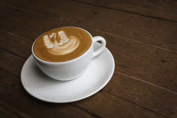White cup of coffee on wooden table in the coffee shop.