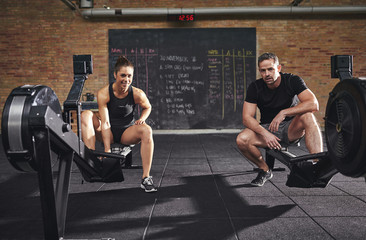 Fototapeta na wymiar Two confident sportsmen sitting on rowing machines