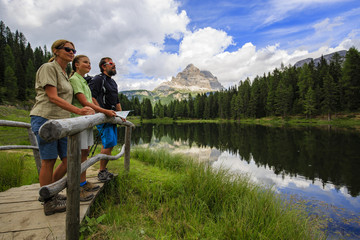 Happy family with teenager taking rest during trekking day on Dolomites mountain in summer time in Italy. Concept of travel, friendly family.