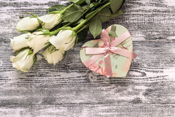 Fresh roses flowers with heart on gray painted wooden background. Place for text.