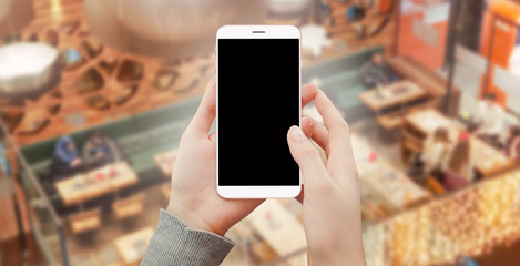 Modern smartphone in female hands in shopping mall