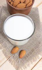 Almond milk with almond on a wooden table.