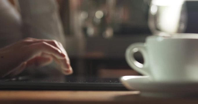 Slow motion of young female hands using notebook on a table in the morning with hot coffee, 4k prores