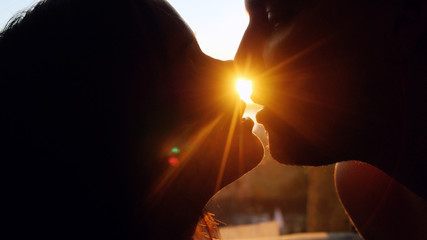 Romantic young couple silhouette is kissing on a sunset with sun shining bright behind them on a...
