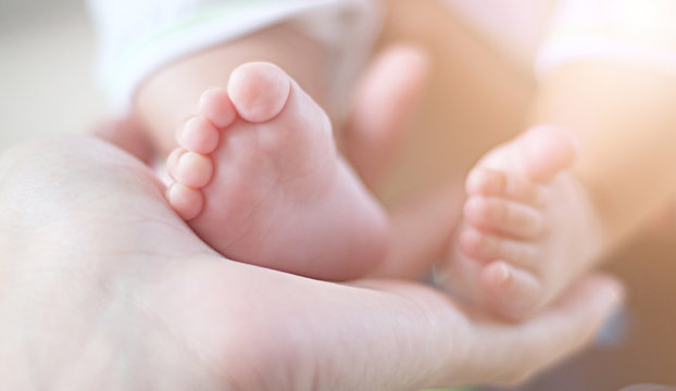 infant feet on hand with orange light