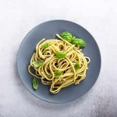 Homemade pasta, spaghetti, linguine with green pesto and basil. Italian healthy food concept with copy space, top view.