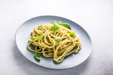 Homemade pasta, spaghetti, linguine with green pesto and basil. Italian healthy food concept with copy space.