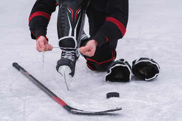 hockey player sitting on the ice to tie shoelaces