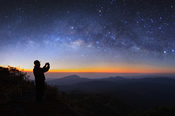 Obraz premium A man take photo milky way galaxy at Doi inthanon Chiang mai, Thailand. Long exposure photograph. With grain