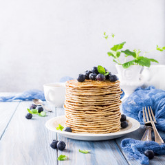 Stack of homemade pancakes with fresh blueberries on a wooden background. Healthy breakfast concept with copy space.