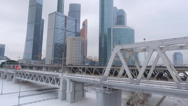 Modern train near Moscow city Russian skyscrapers. Lastochka second metro ring. Subway intersection. Highway. Unique aerial drone 4K footage. Winter day snow. Bridge.