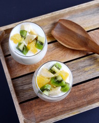 Fresh colorful vitamin breakfast yogurt pieces fruits kiwi banana orange in glass cups