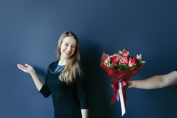 Cute girl getting bouquet of red tulips. Boyfriend giving tulips.