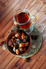 Bowl of dried dates on old wooden table with tea
