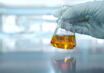 hand with orange solution in scientist hand with science laboratory