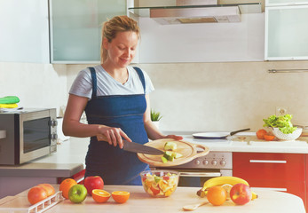 pregnant woman on kitchen making healthy fruit salad