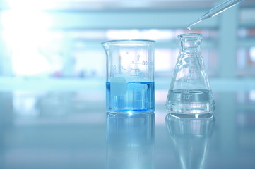 beaker and flask with blue solution and drop of water in science