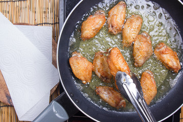 Chef frying chicken wings in pan