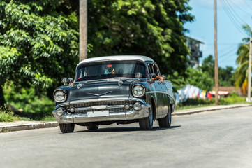 HDR - Schwarzer amerikanischer Oldtimer mit weissem Dach fährt auf der Landstraße im Vorort von Santa Clara Cuba - Serie Kuba Reportage