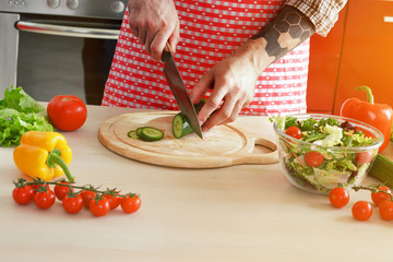 male hands cutting cucumber with knife