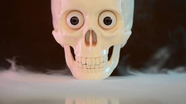 skull on smooth smoke surface at dark background