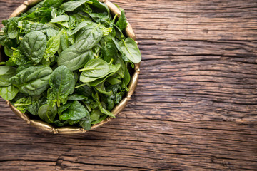 Spinach leaves.Fresh spinach leaves in retro bowl on oak wood board. Selective focus.