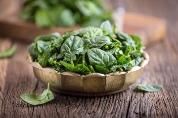 Spinach leaves.Fresh spinach leaves in retro bowl on oak wood board. Selective focus.