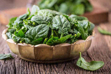 Spinach leaves.Fresh spinach leaves in retro bowl on oak wood board. Selective focus.