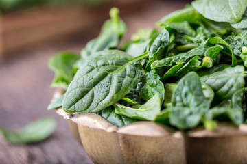 Spinach leaves.Fresh spinach leaves in retro bowl on oak wood board. Selective focus.