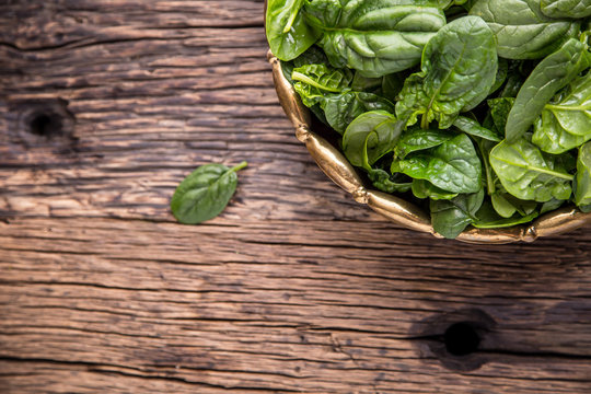 Spinach leaves.Fresh spinach leaves in retro bowl on oak wood board. Selective focus.