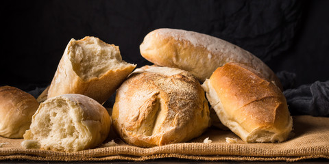 Freshly baked bread loaves on burlap dark wooden background. Texture closeup italian bakery products