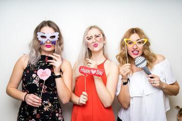 three happy young ladies girls strike a pose on white background photo booth with party props