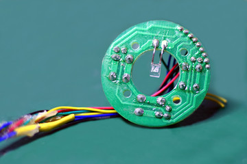 Close up of small circular printed circuit board, PCB with wires.