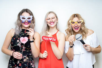 three happy young ladies girls strike a pose on white background photo booth with party props © Peter