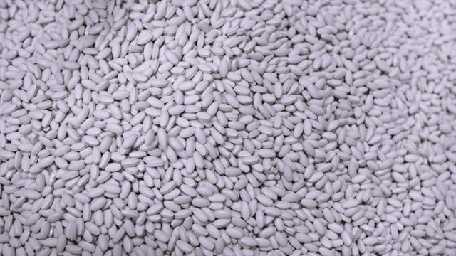 Pill Production. Closeup slow motion shot of many white pills falling out of pill manufacturing machin