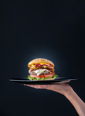 Delicious fresh homemade burger on a black plate - obrazy, fototapety, plakaty