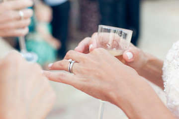 Bride with wedding ring holds a glass of champagne - Powered by Adobe