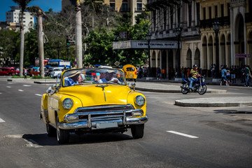 Fototapeta na wymiar HDR - Auf der Hauptstrasse in Havanna Kuba fahrender amerikanischer gelber Cabriolet Oldtimer mit Touristen - Serie Kuba Reportage