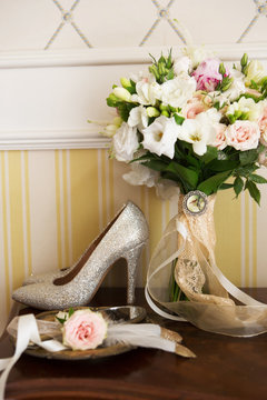 Wedding decoration: shoes, rings and bouquet on a table