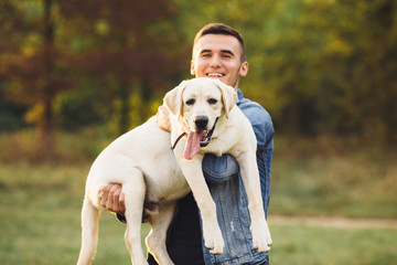 Portrait of happy man holding dog Labrador in hands in park