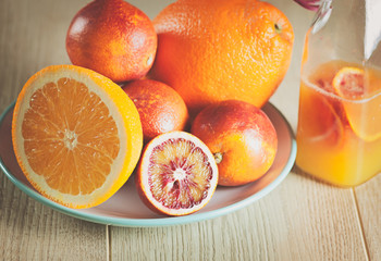 bottle with a fresh juice from the oranges and blood oranges on a wooden surface