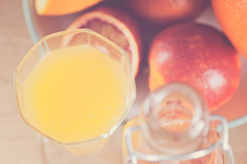 bottle with a fresh juice from the oranges and blood oranges on a wooden surface