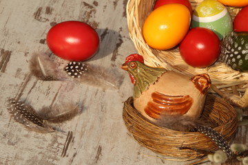 Easter, Osterdekoration, Ein Keramikhuhn sitzt neben einem Korb mit Ostereiern