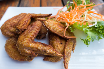 Chichen wing fried with salad in white dish on wooden table