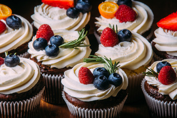 Fresh tasty chocolate cupcakes with berries. Selective focus. Dark wooden background.Rustic style, place for text.