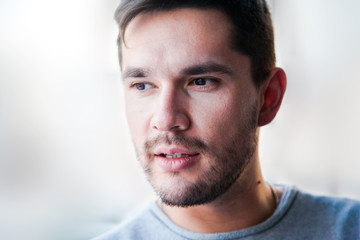 Handsome man looking forward and thinking. Close up portrait of caucasian man. Brunette on the blurry background