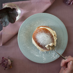 Traditional Swedish semla on a plate with hand holding spoon closeup from above 