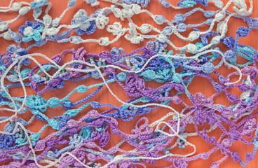 Bright, colorful original crochet handmade background with white cotton ribbons. Selective soft focus. Easter, spring, summer needlework backdrop, creative craft work