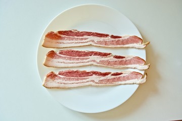 Smoked bacon on the white plate on the white table 